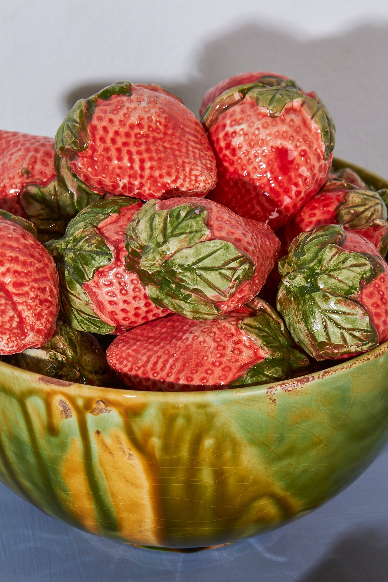 Tazón verde con fresas de cerámica roja y verde, decoración vibrante y estilo rústico moderno.