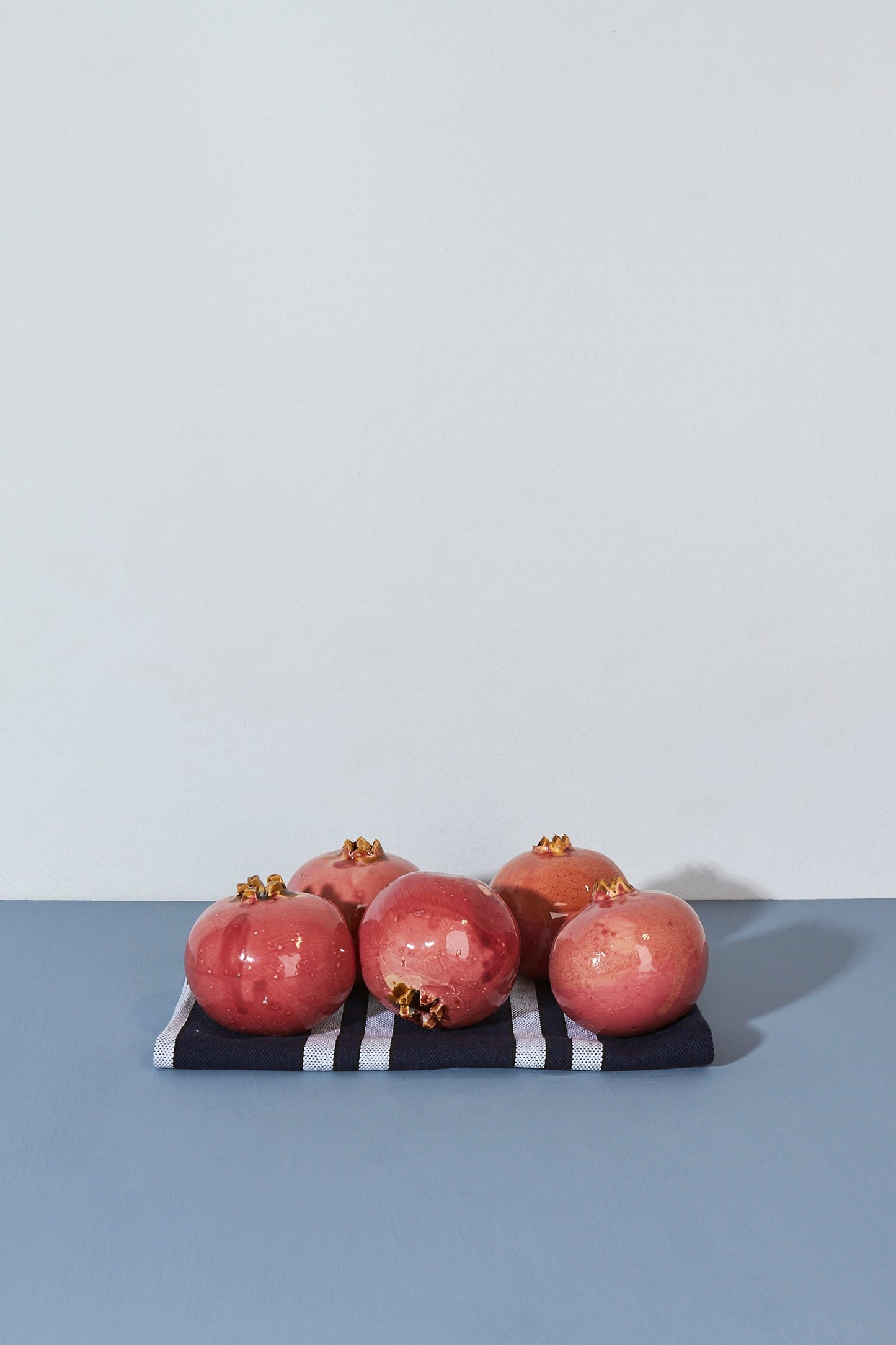 Granadas rosadas sobre una servilleta de rayas azules y blancas, con un fondo minimalista.