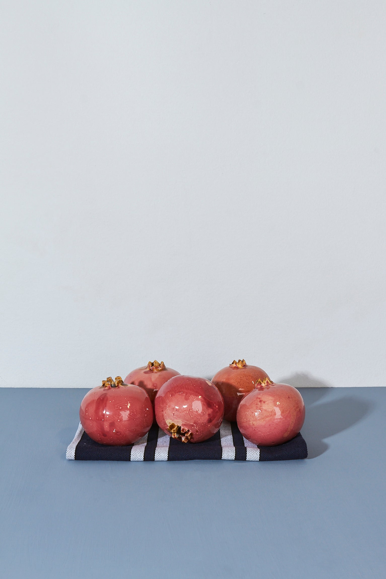 Granadas rosadas sobre una servilleta de rayas azules y blancas, con un fondo minimalista.