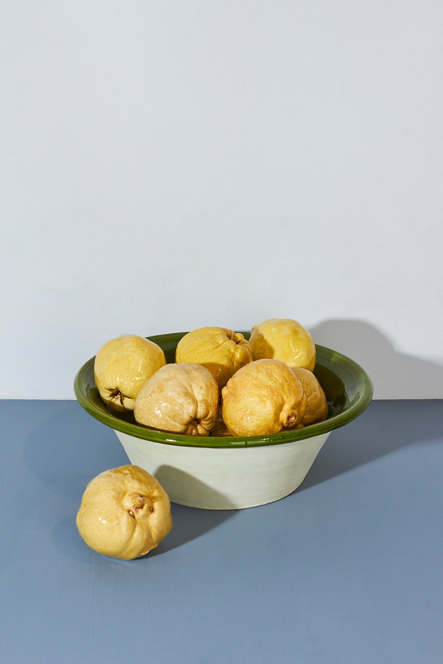 Tazón de cerámica verde y blanco con limones amarillos, estilo moderno y minimalista.