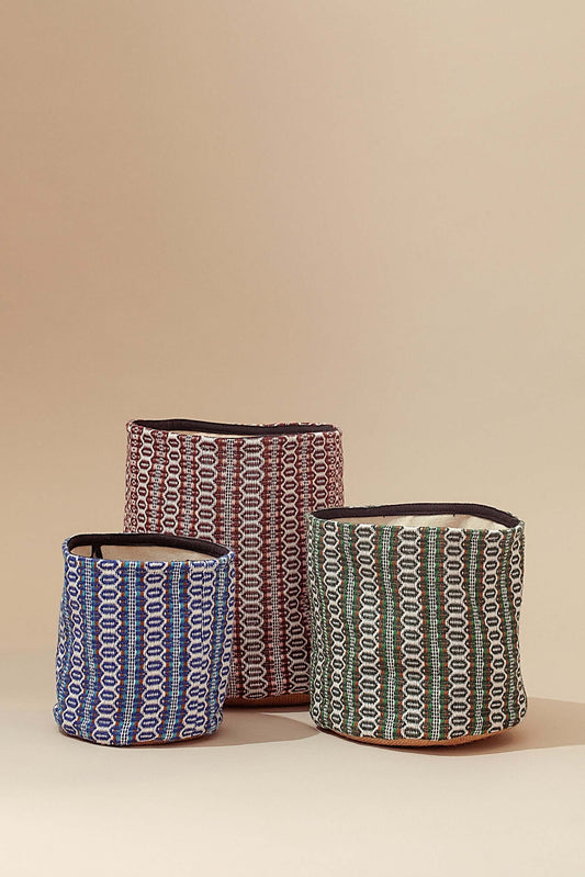 Tres cestos de tela con estampado retro ojo de perdiz en azul, granate y verde, sobre fondo liso de color neutro.