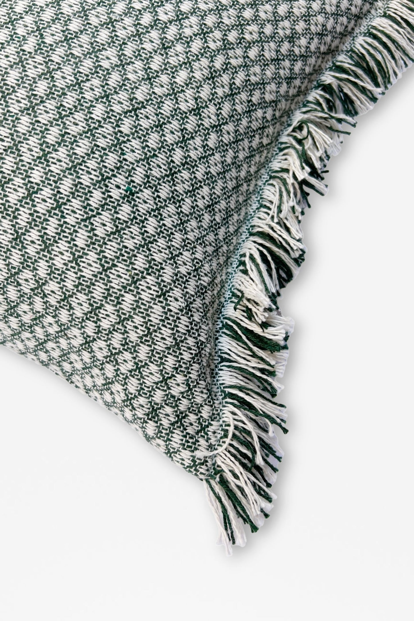 Cojín verde con textura de patrón, borde con flecos en tonos blanco y verde, estilo moderno y acogedor.