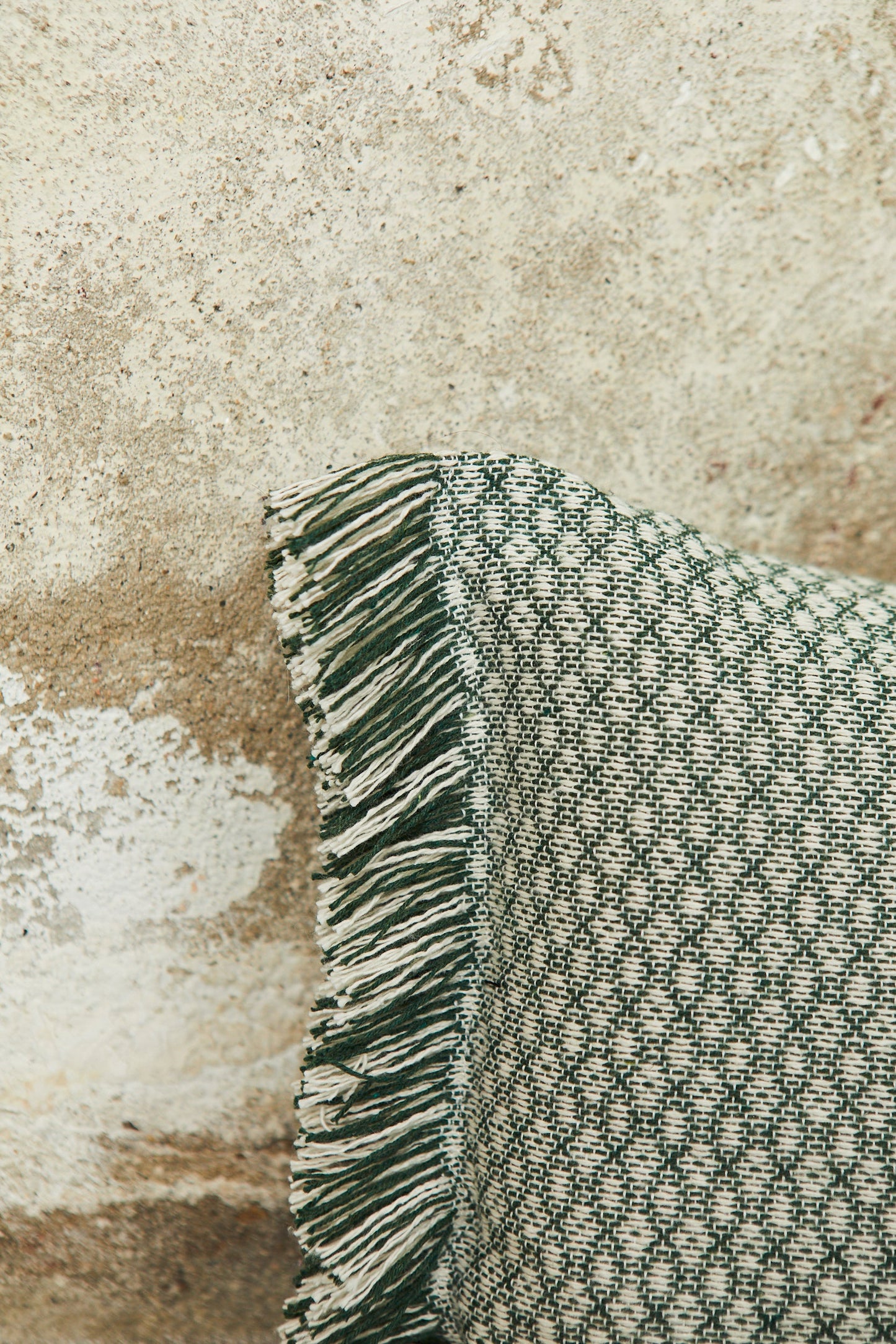Cojín verde con diseño de cuadros y flecos, ideal para decoración rústica y contemporánea.
