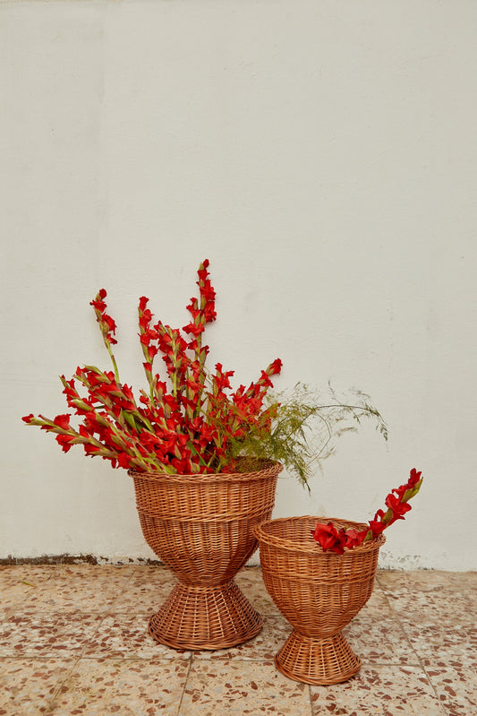 Cestas de mimbre trenzado en tonos marrones, con flores rojas y verdes, estilo bohemio para decoración.
