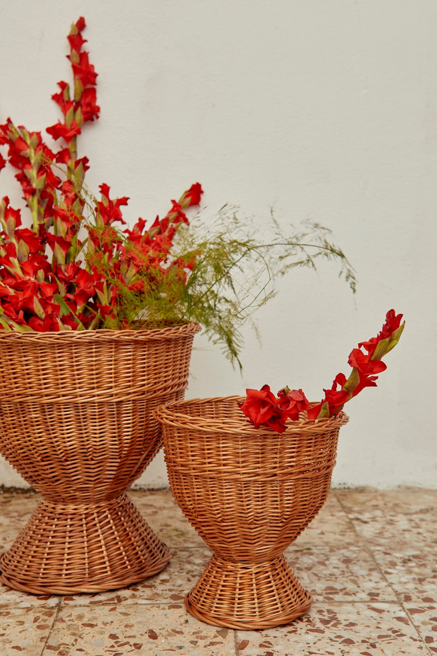 Cestas de mimbre marrón con flores rojas, diseño moderno, tamaños grandes y pequeños, perfectas para decoración.