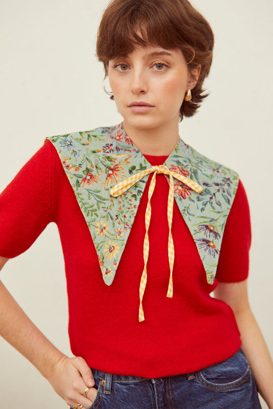 Cuello falso jacquard en tono celeste con estampado de azaleas y lazo delantero a cuadros vichy en color amarillo.