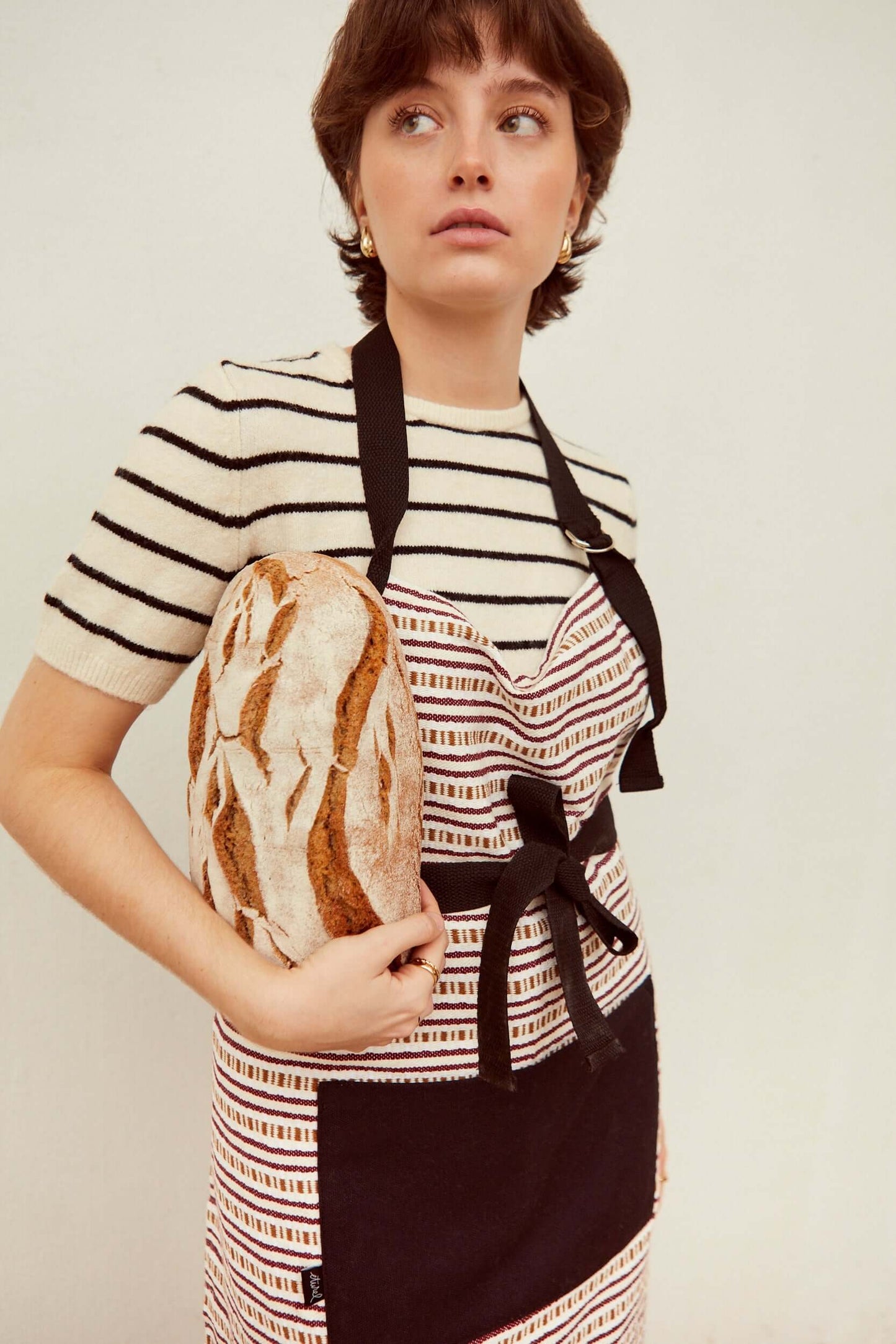 Vista lateral de mujer - Detalle delantal tejido cadena granate con cintas marrones ajustables y bolsillo - delantal artesanal confeccionado España