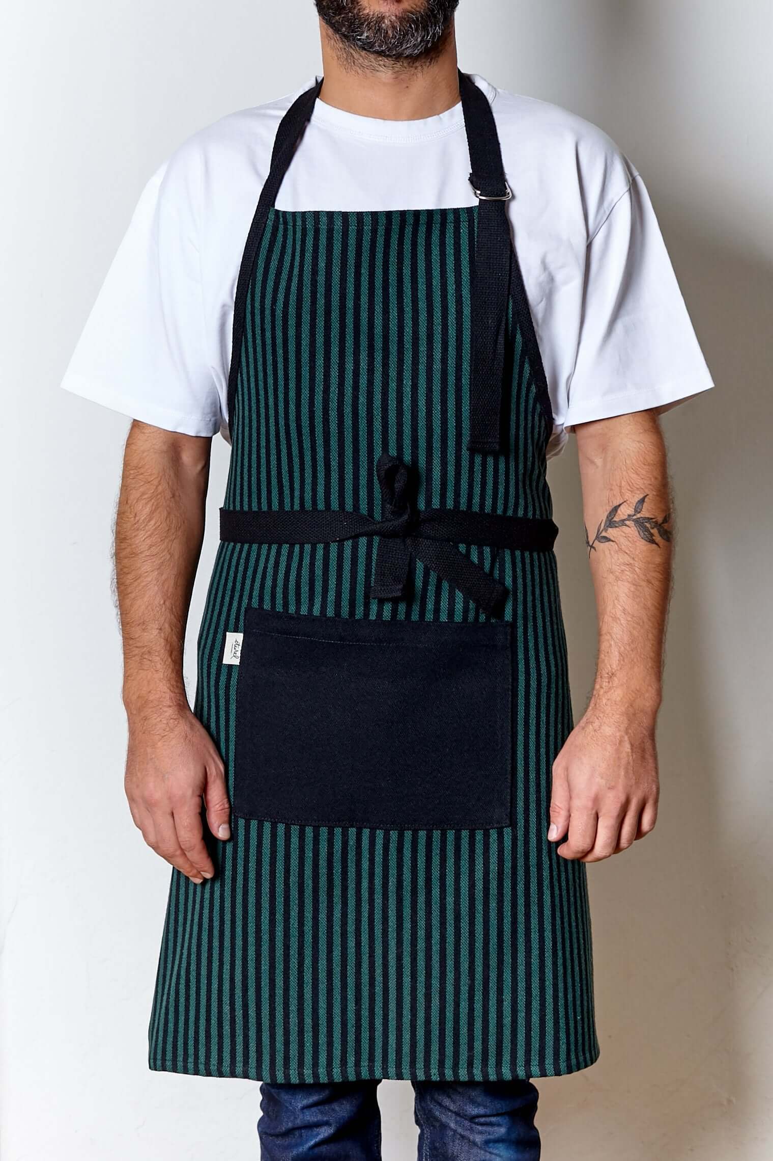 Hombre usando delantal loneta estribera verde ajustable con bolsillo negro en cocina