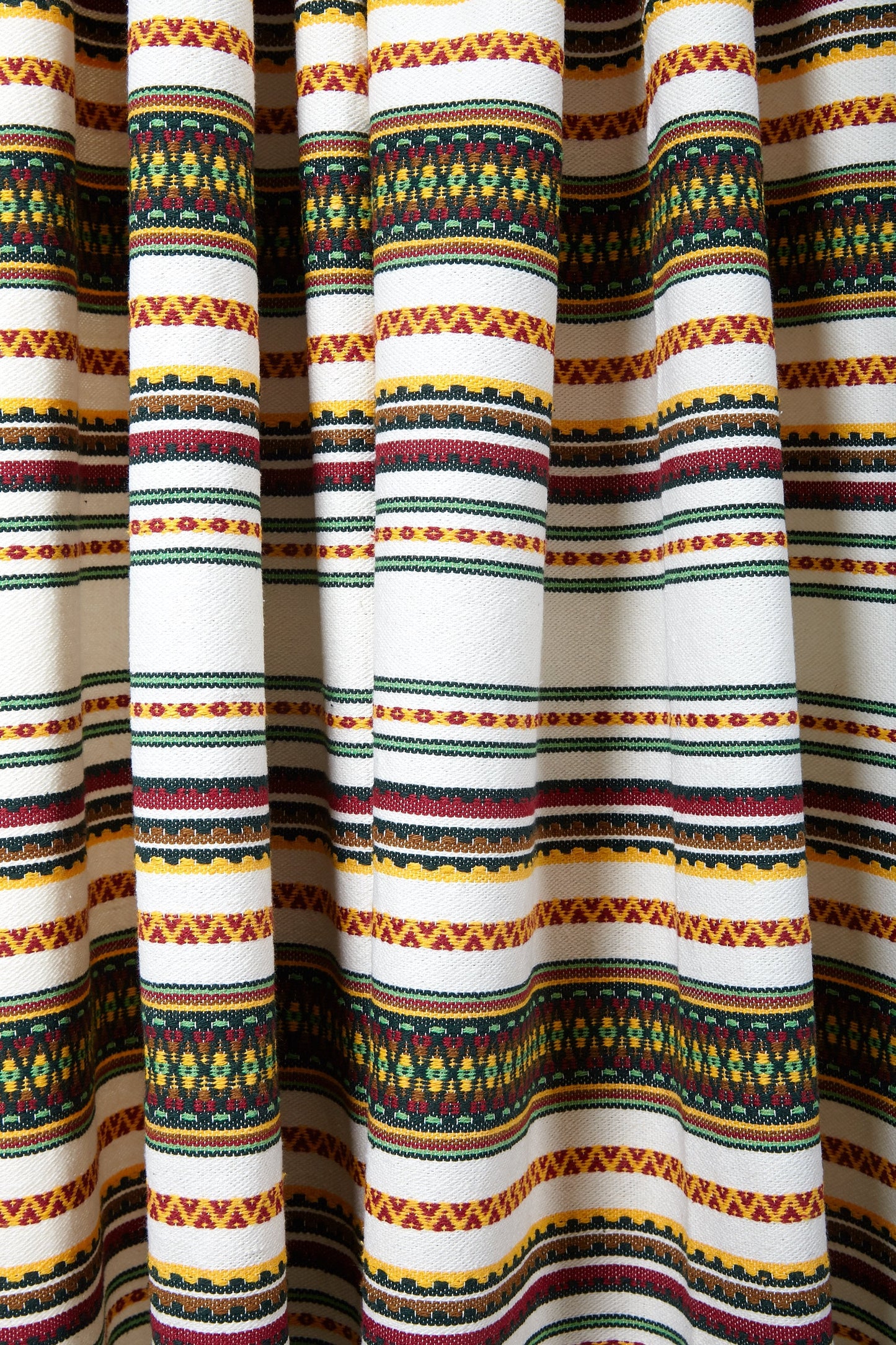 Tela de algodón blanco con estampado azteca en colores rojo, amarillo y verde, ideal para decoraciones artesanales.