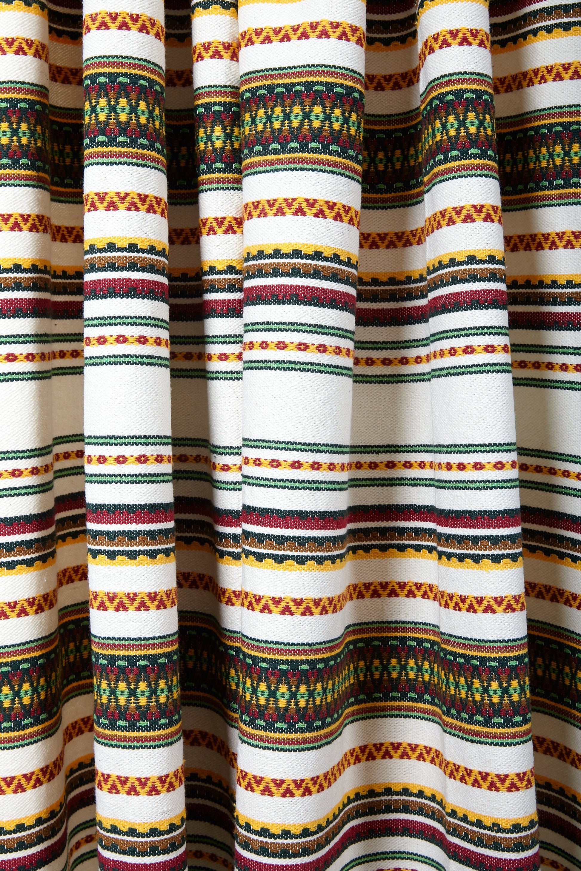 Tela de algodón blanco con estampado azteca en colores rojo, amarillo y verde, ideal para decoraciones artesanales.