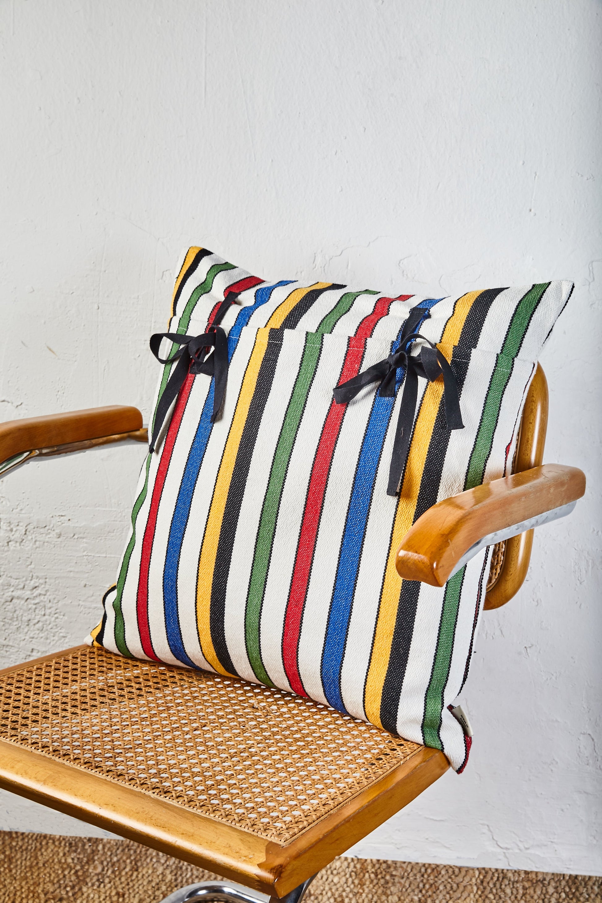 Cojín de rayas multicolores, algodón, con lazos negros, estilo moderno, ideal para decorar.