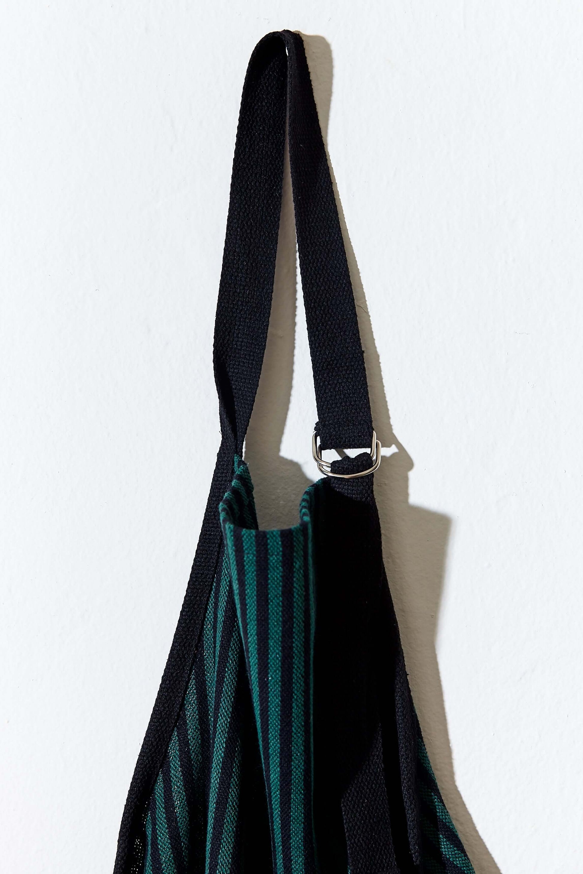 Delantal loneta estribera verde colgado mostrando anilla metal y tiras ajustables