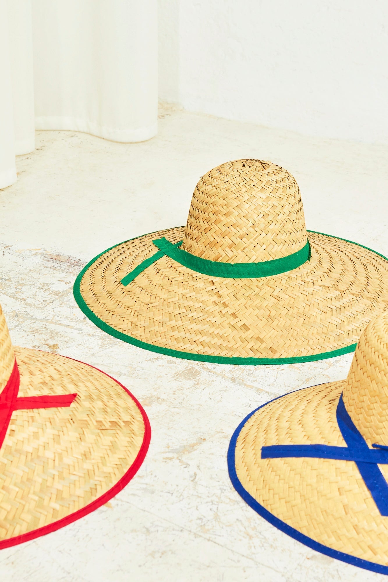 Sombreros de paja con cintas en verde, rojo y azul; estilo veraniego, perfectos para el sol.