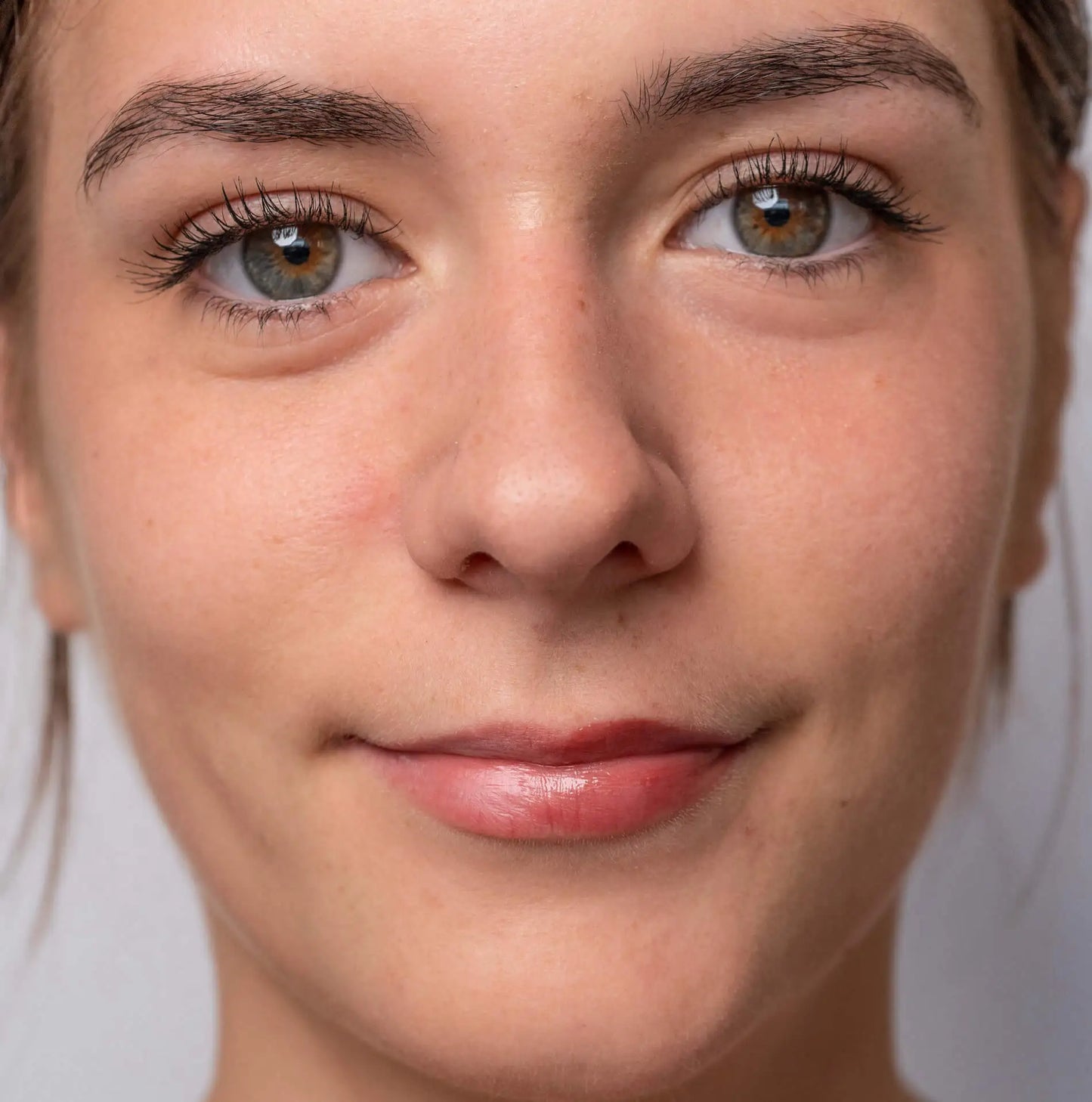Gros plan sur une femme aux lèvres hydratées, portant un baume teinté Trew Cosmetic au fini brillant et naturel.