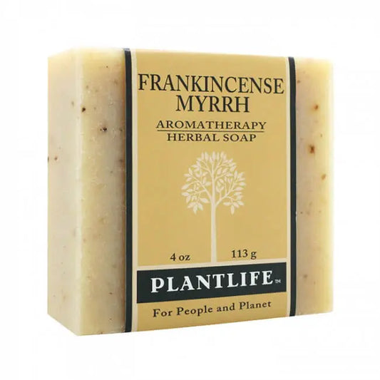 A rectangular bar of speckled beige herbal soap wrapped in a tan paper label with a tree logo and black text.