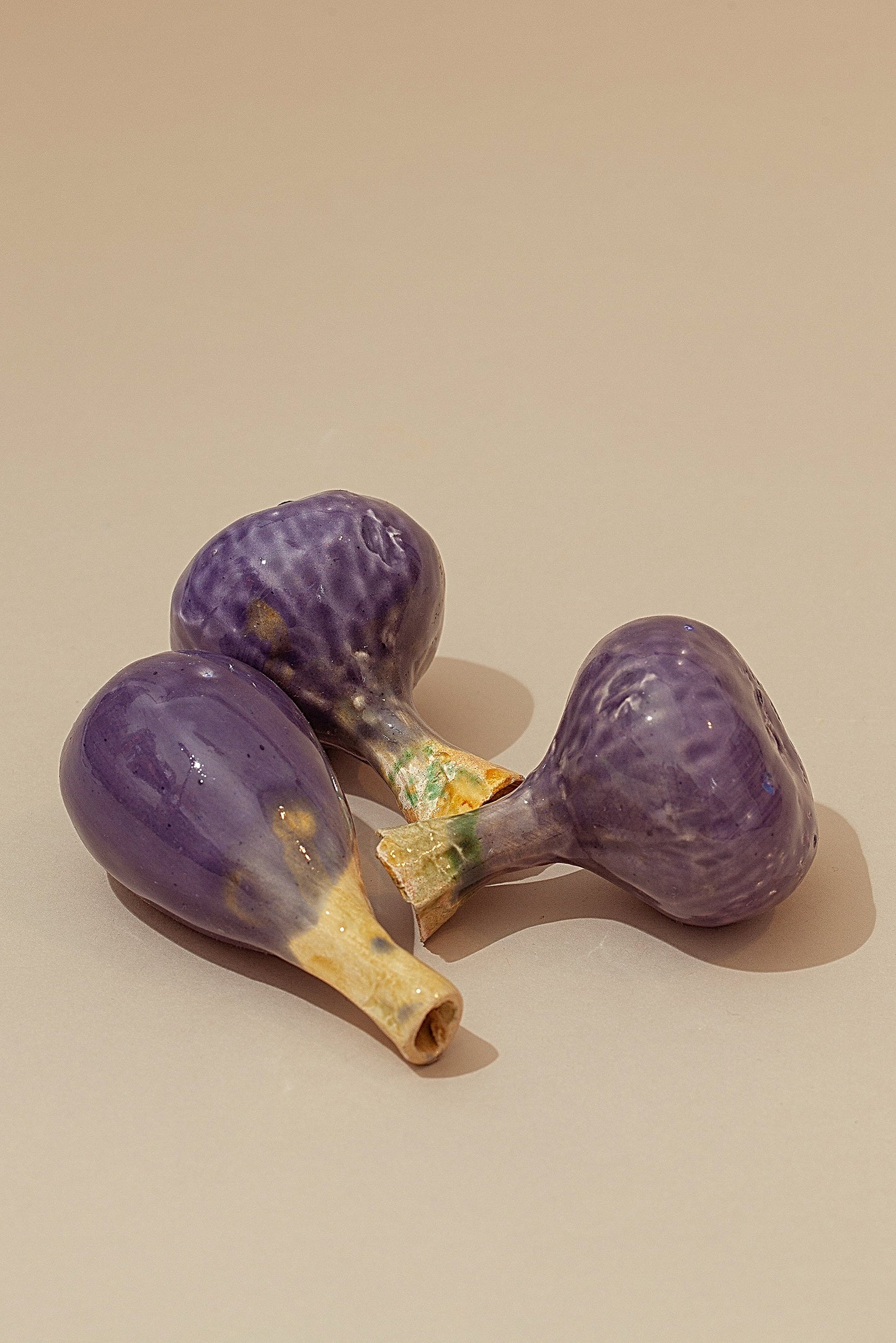 Figuras decorativas de cerámica en forma de higos morados, con detalles en tonos crema y verdes.