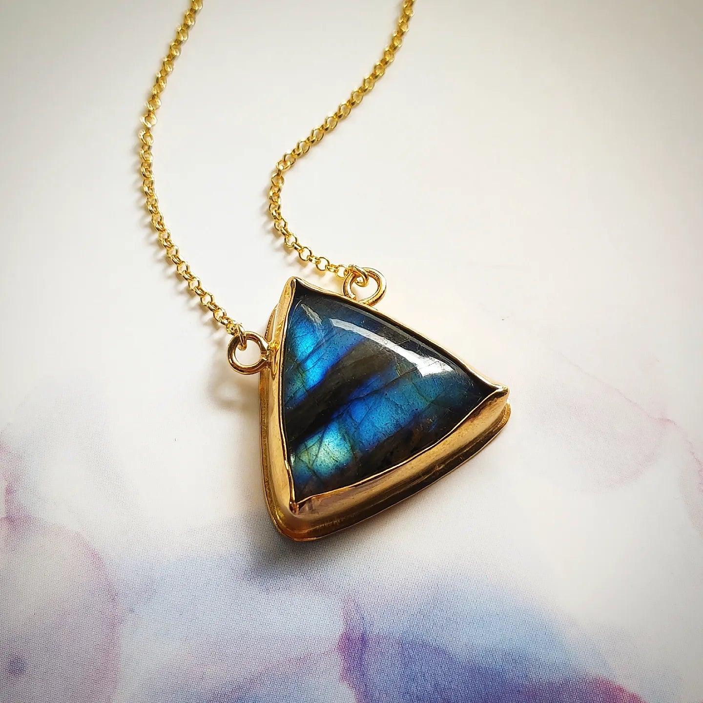 Collar dorado con piedra triangular de labradorita azul, elegante y brillante. Ideal para ocasiones especiales.