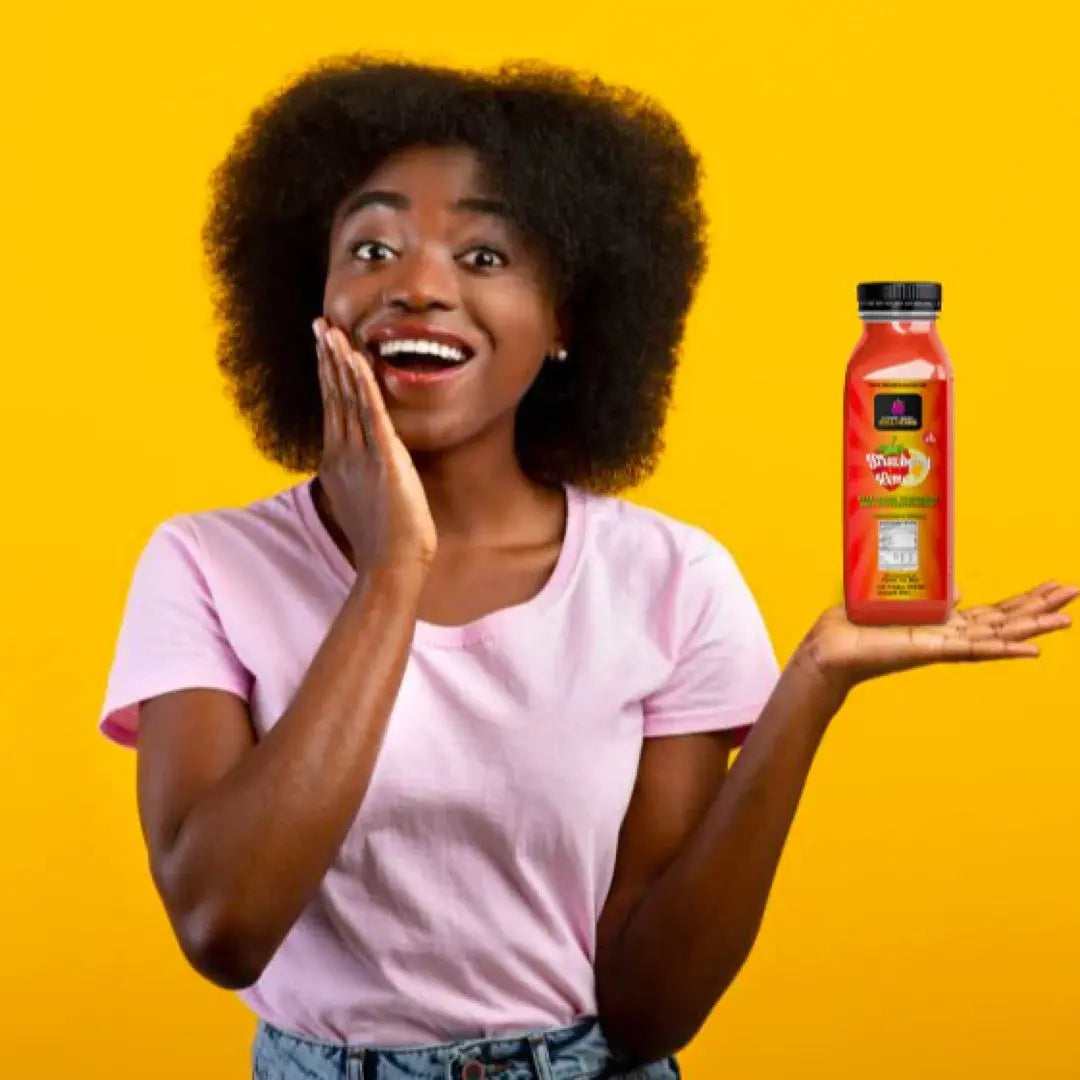 A woman in a pink shirt against a yellow background holding a 12 oz bottle of strawberry sea moss lemonade.