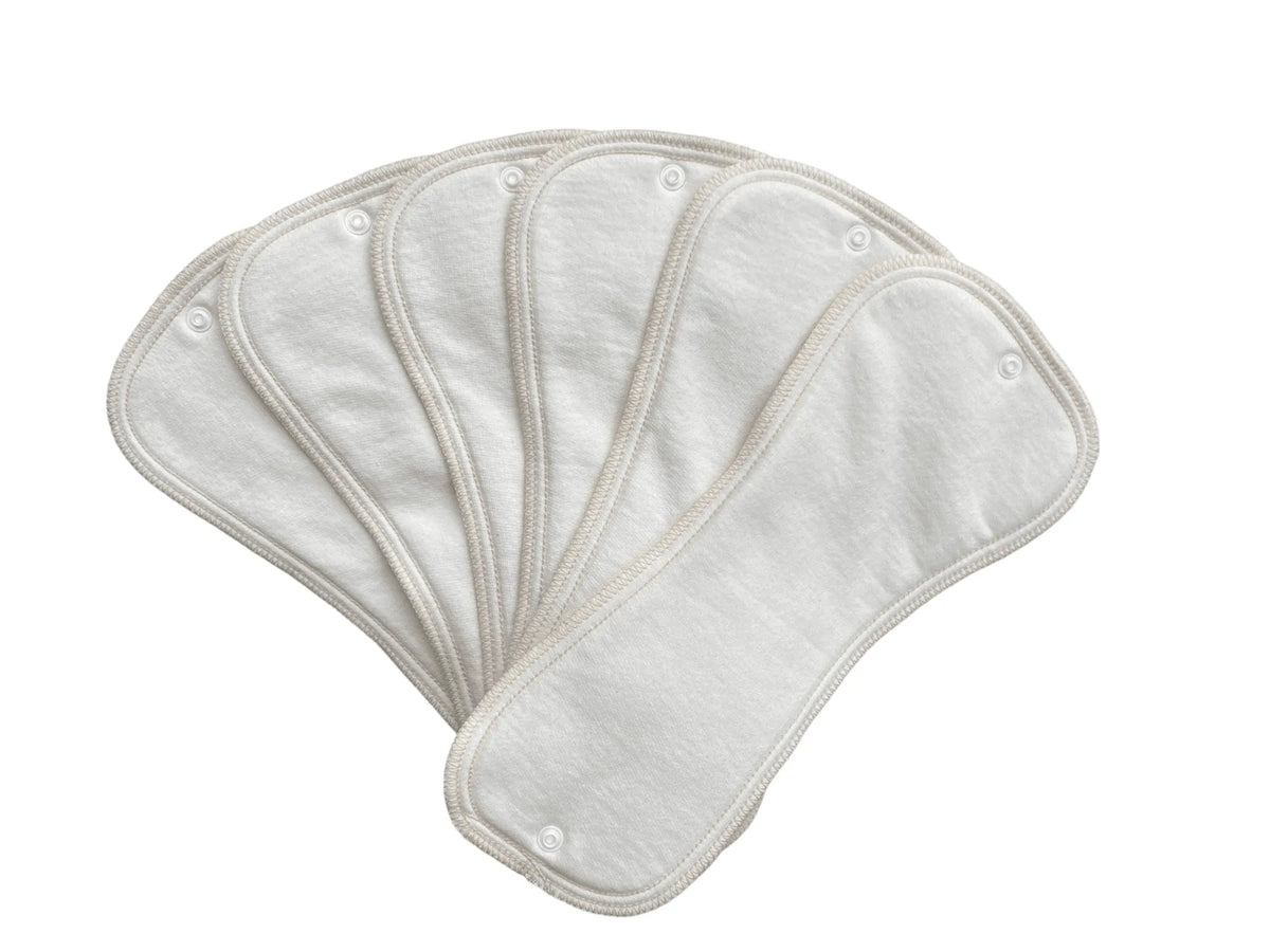 Five off-white, hourglass-shaped fabric diaper inserts with snap buttons, fanned out against a white background.