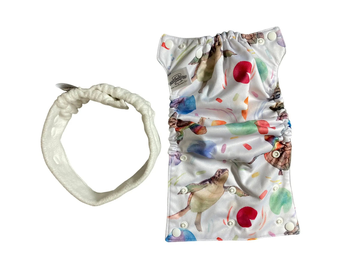 Turtle-print PUL diaper cover with white snaps and a matching white fleece belt, set against a plain background.