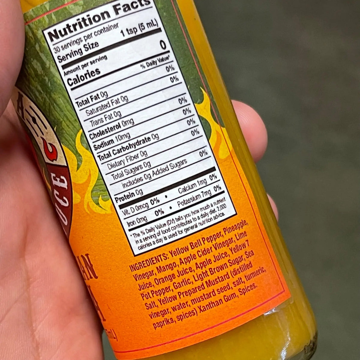 Close-up of a Hawaiian Lava hot sauce bottle, showing the yellow sauce, nutrition facts, and ingredient list.