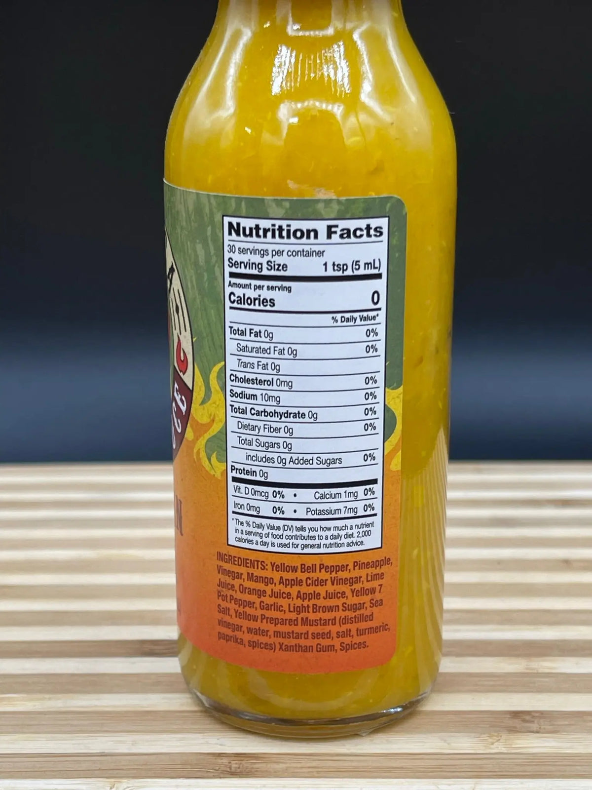 Bottle of Hawaiian Lava hot sauce with a yellow textured sauce, showing a nutrition facts label on a wooden surface.
