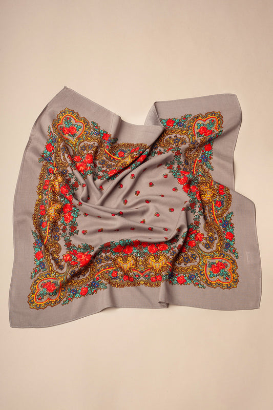 Grey square scarf with vibrant floral chain patterns in red, yellow, and blue, featuring a soft, folded fabric look.