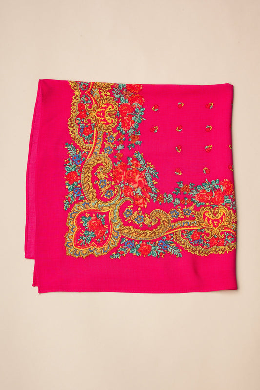 Pañuelo rosa fucsia estilo portugués con estampado floral, detalles de cadenas doradas y flores rojas y azules.