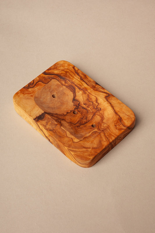 Jabonera rectangular de madera de olivo con veteado natural, acabado liso y orificios de drenaje sobre fondo neutro.