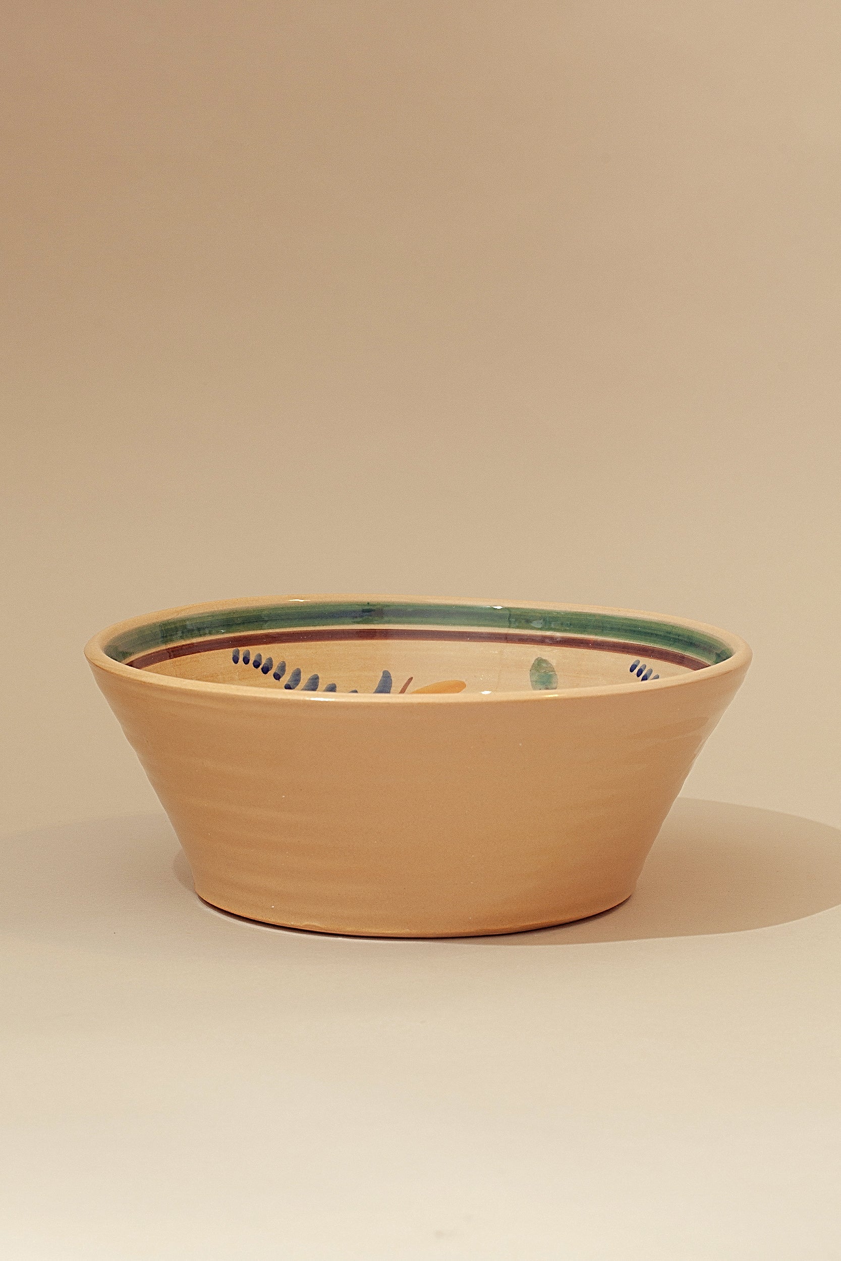 Cuenco de cerámica color terracota con borde verde, decorado en estilo floral, ideal para servir y decorar.