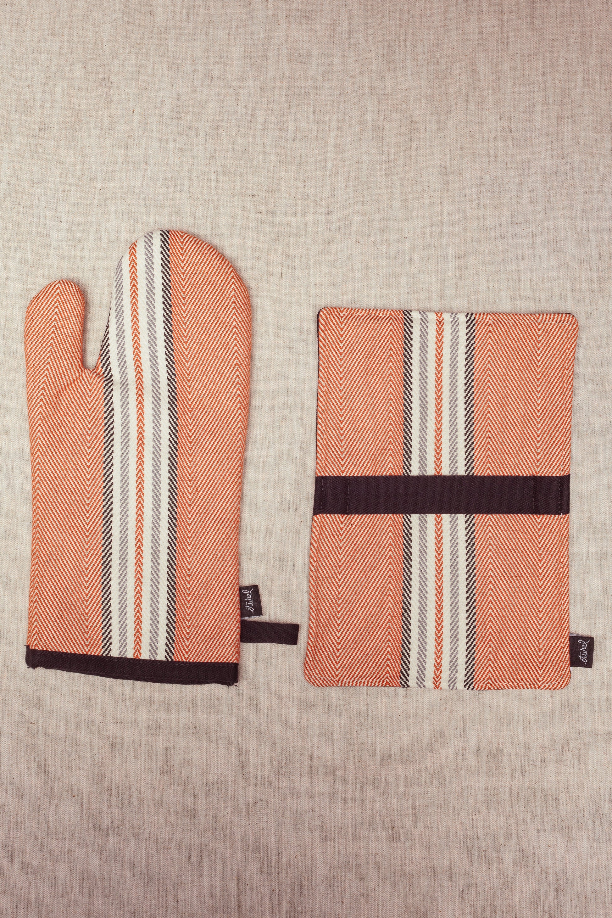 Manopla y salvamanteles de algodón en tonos naranja, blanco y negro con diseño de rayas. Ideal para cocina.