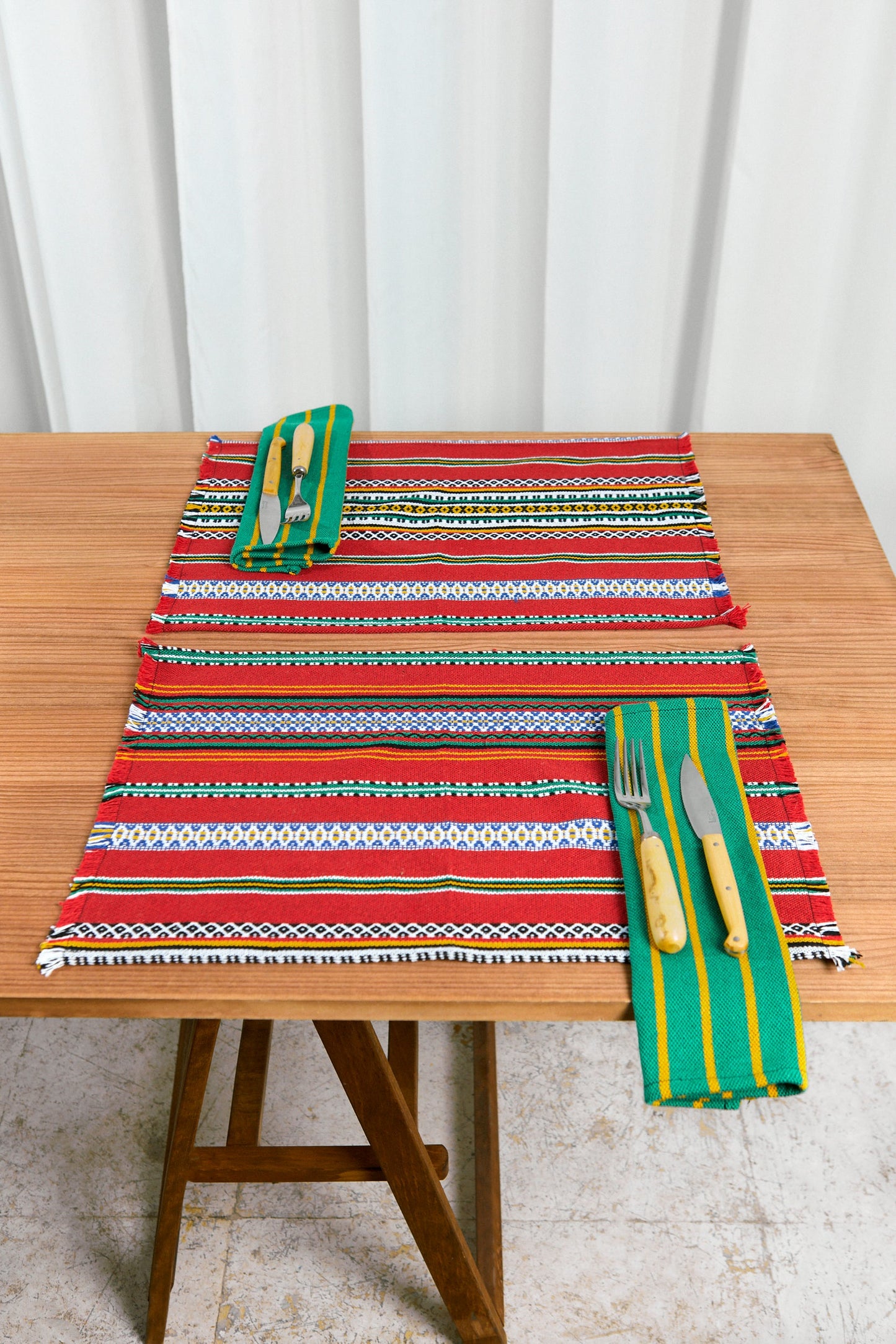 Mantel de mesa colorido rojo, verde y amarillo, tejido artesanal, con cubiertos y servilletas a juego.