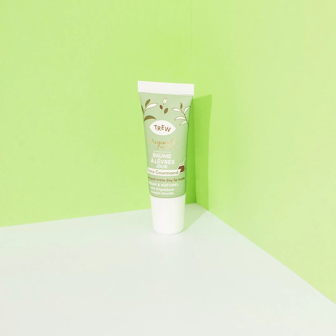 A light green squeeze tube of lip balm with botanical illustrations, set against a vibrant lime green corner background.