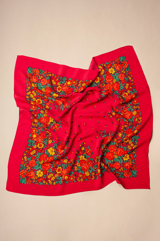 Pañuelo cuadrado de color rosa intenso con estampado de flores tradicionales en tonos rojos, amarillos y hojas verdes.