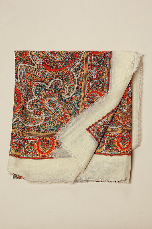 Pañuelo de lana blanco con estampado paisley multicolor y bordes deshilachados sobre fondo neutro.