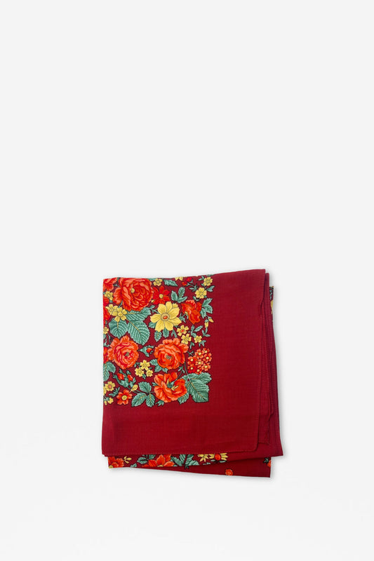 Pañuelo granate doblado con estampado de flores coloridas en tonos rojos, naranjas y amarillos sobre fondo liso.