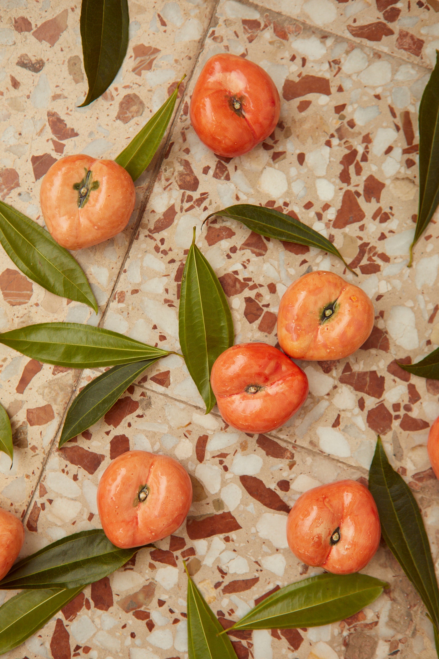 Mangos rosas frescos sobre fondo de mosaico con hojas verdes, ideal para postres y ensaladas.