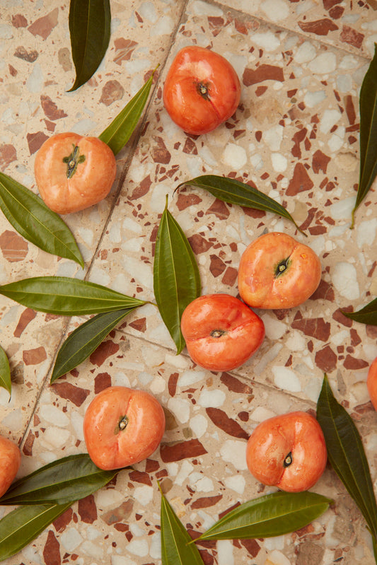 Mangos rosas frescos sobre fondo de mosaico con hojas verdes, ideal para postres y ensaladas.