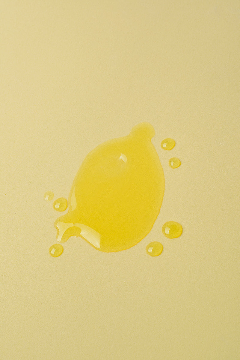 Gota de aceite amarillo brillante sobre fondo amarillo suave, ideal para productos de belleza o cocina.
