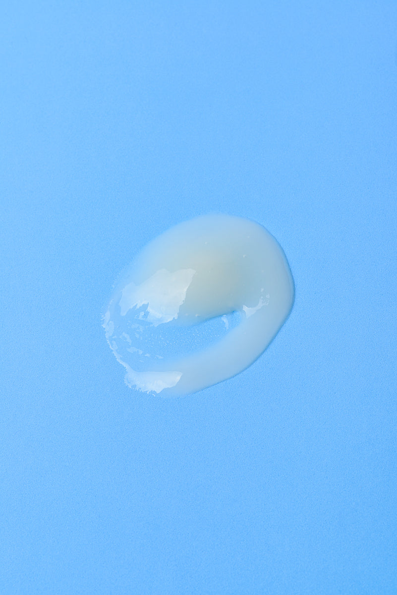 Gel transparente brillante en fondo azul, textura suave y ligera, ideal para cuidado de la piel.