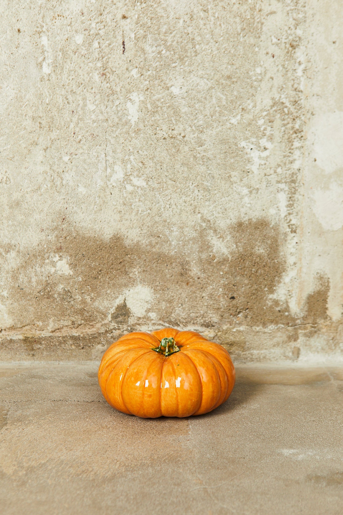 Calabaza naranja brillante sobre superficie de cemento, ideal para decoración otoñal y festividades.