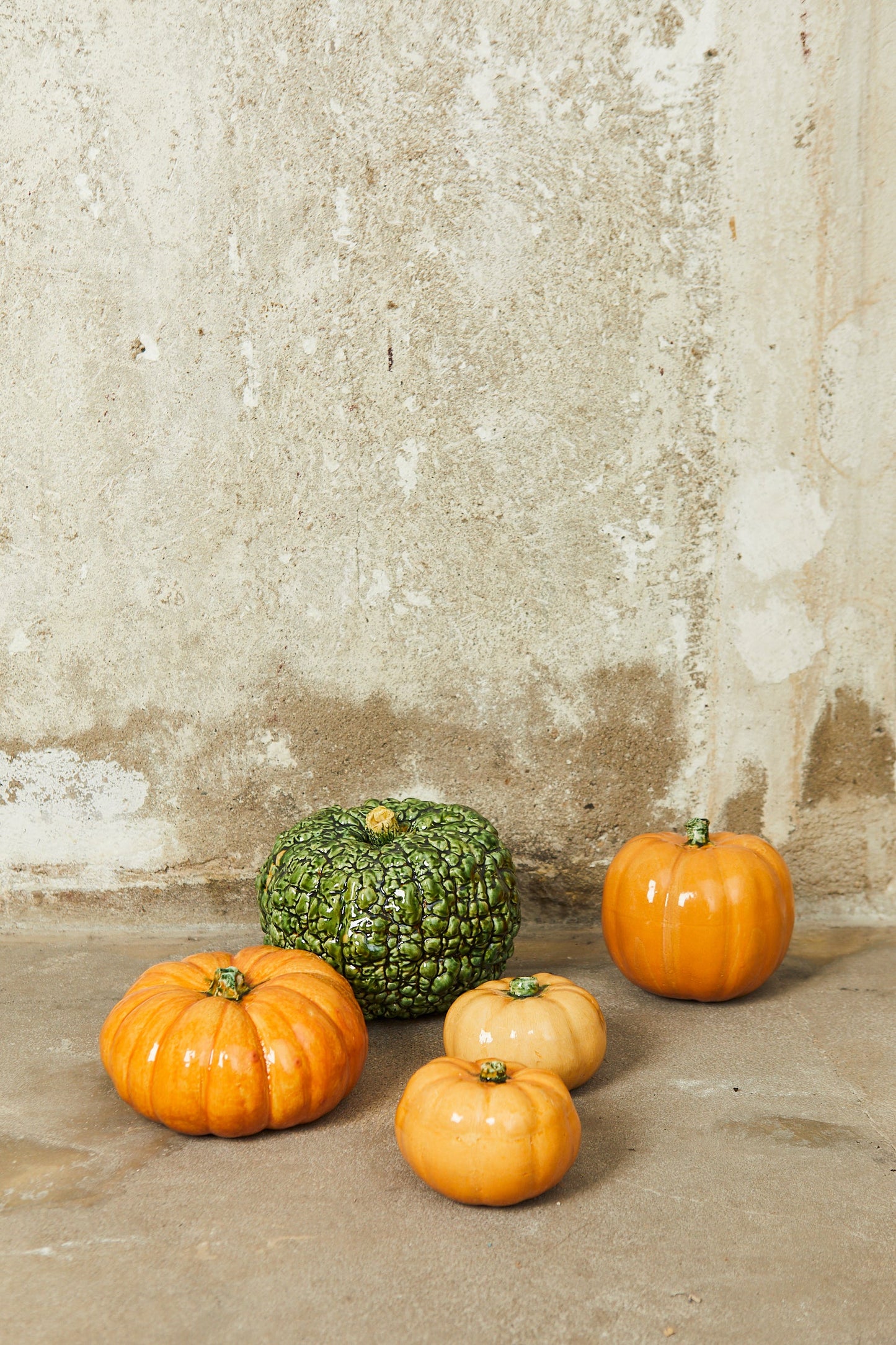 Calabazas decorativas en tonos naranja, verde y beige, hechas de cerámica, estilo rústico para otoño.