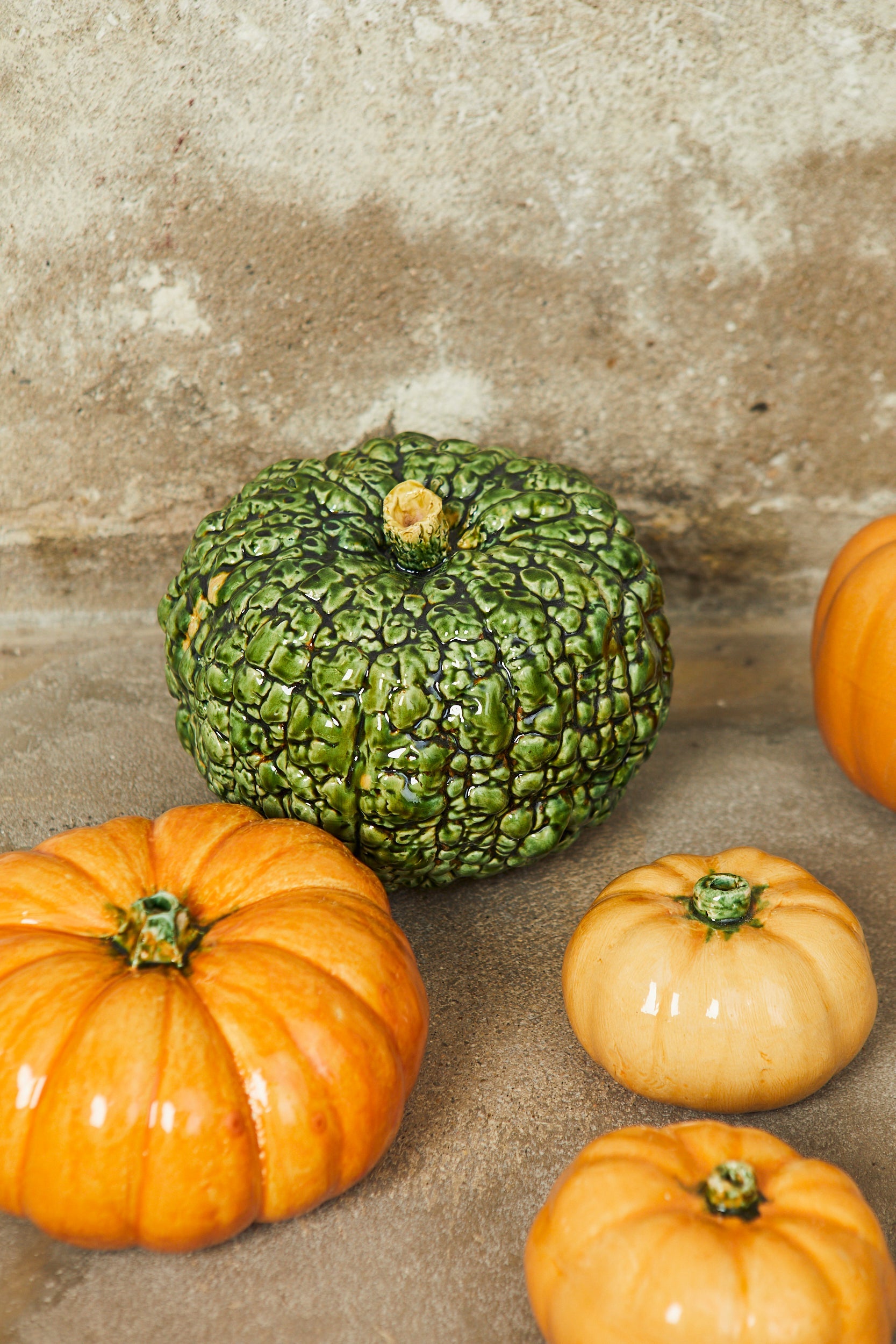 Calabazas de cerámica en tonos verde, naranja y crema, con acabado brillante, perfectas para decoración.
