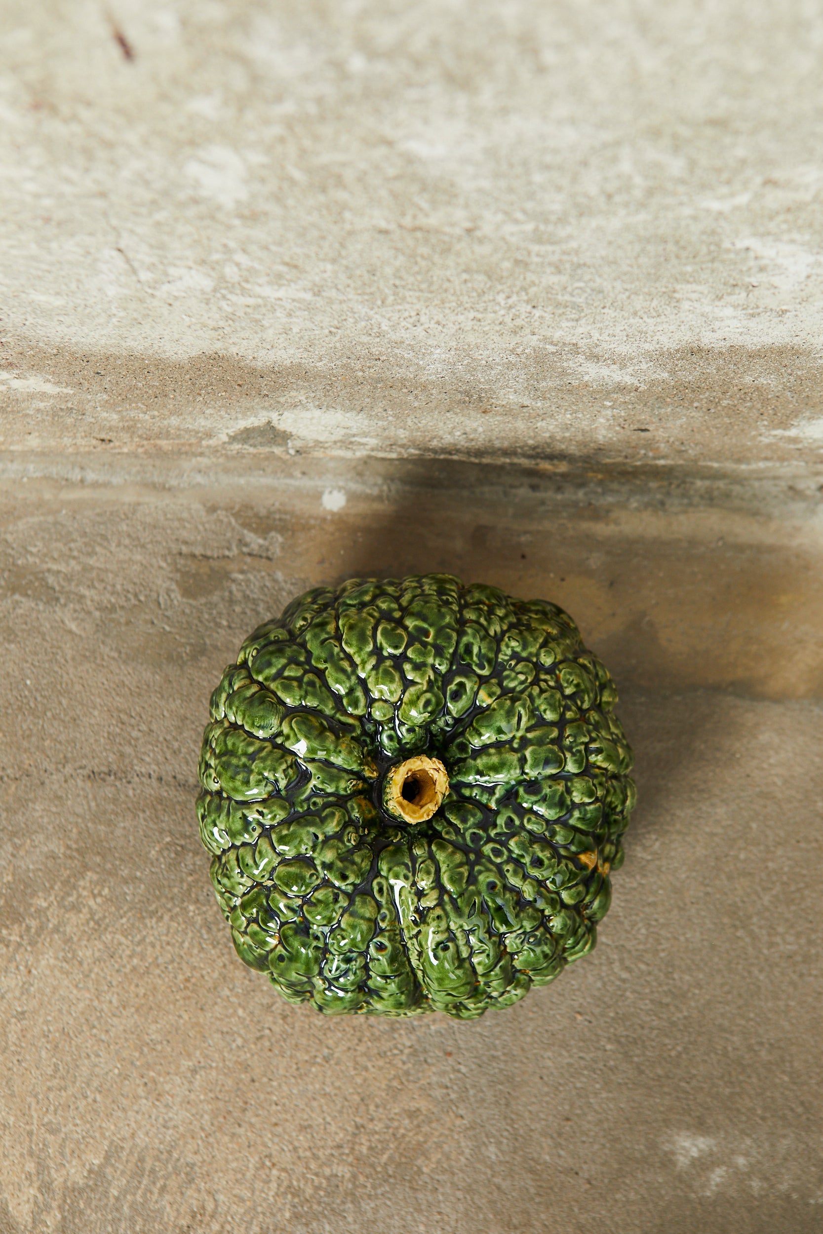Calabaza verde de cerámica brillante con textura arrugada, ideal para decoración rústica y artesanal.
