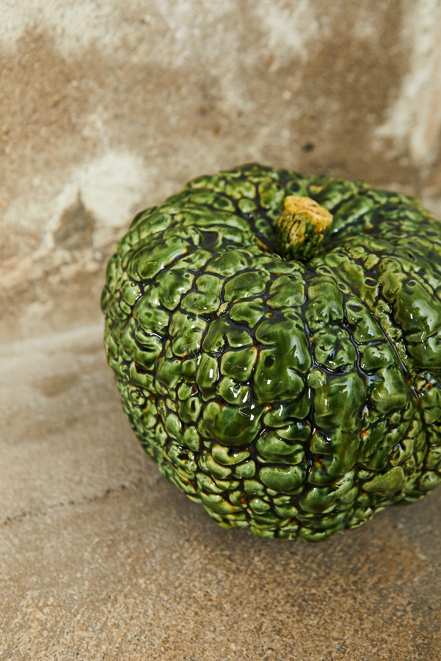 Calabaza decorativa de cerámica verde brillante con textura arrugada, ideal para adornos rústicos y naturales.