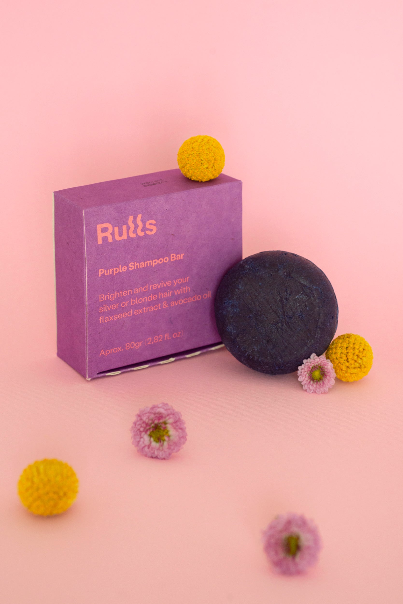 Champú sólido morado de 80g con extracto de lino y aceite de aguacate, presentado en caja lila. Ideal para cabello rubio.