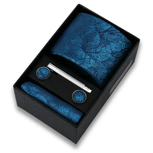 Conjunto de corbata azul con pañuelo, gemelos y pasador en caja, diseño de hojas azules.