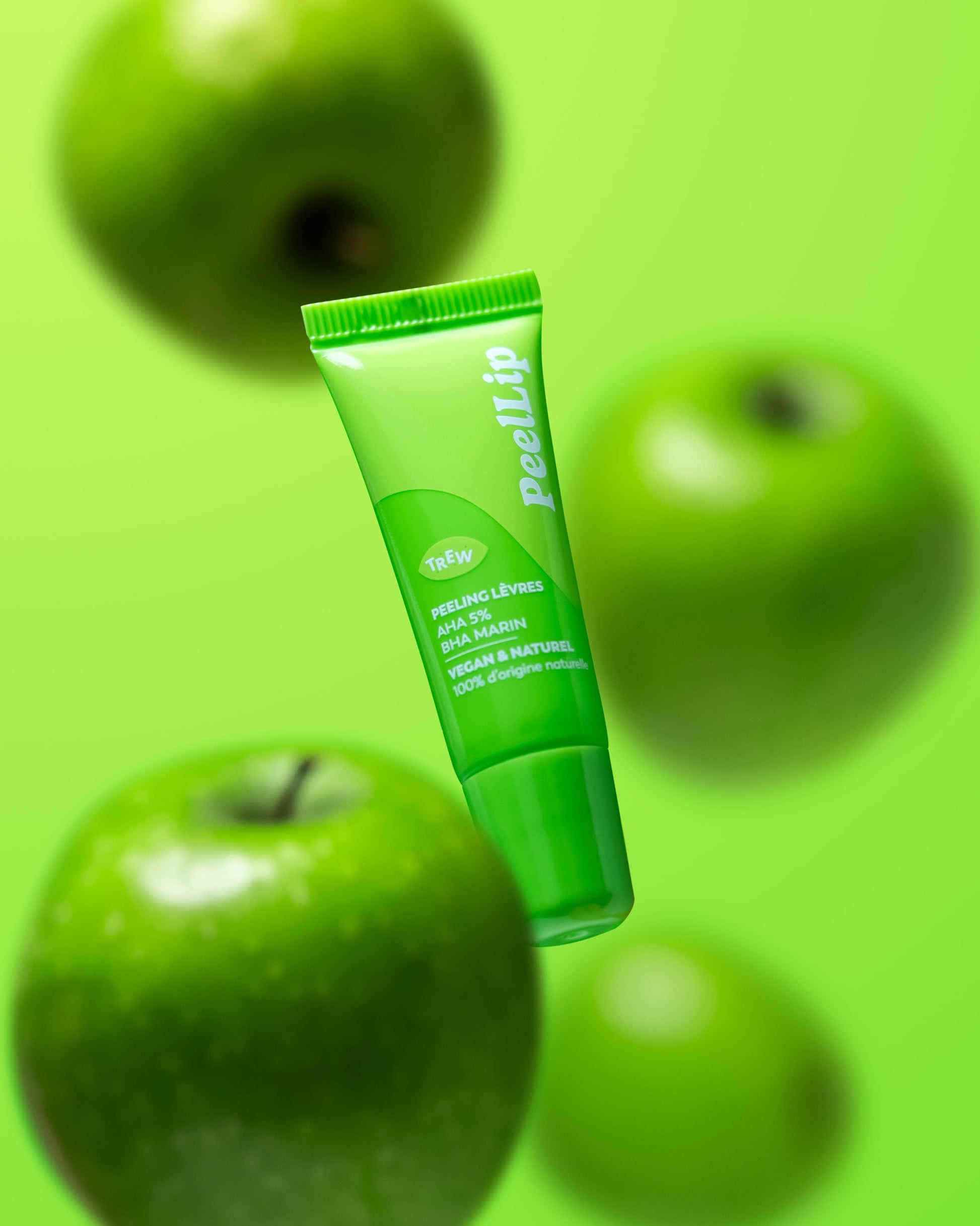 Bright green lip peeling tube labeled "PeelLip" floating against a vibrant green background with blurred green apples.