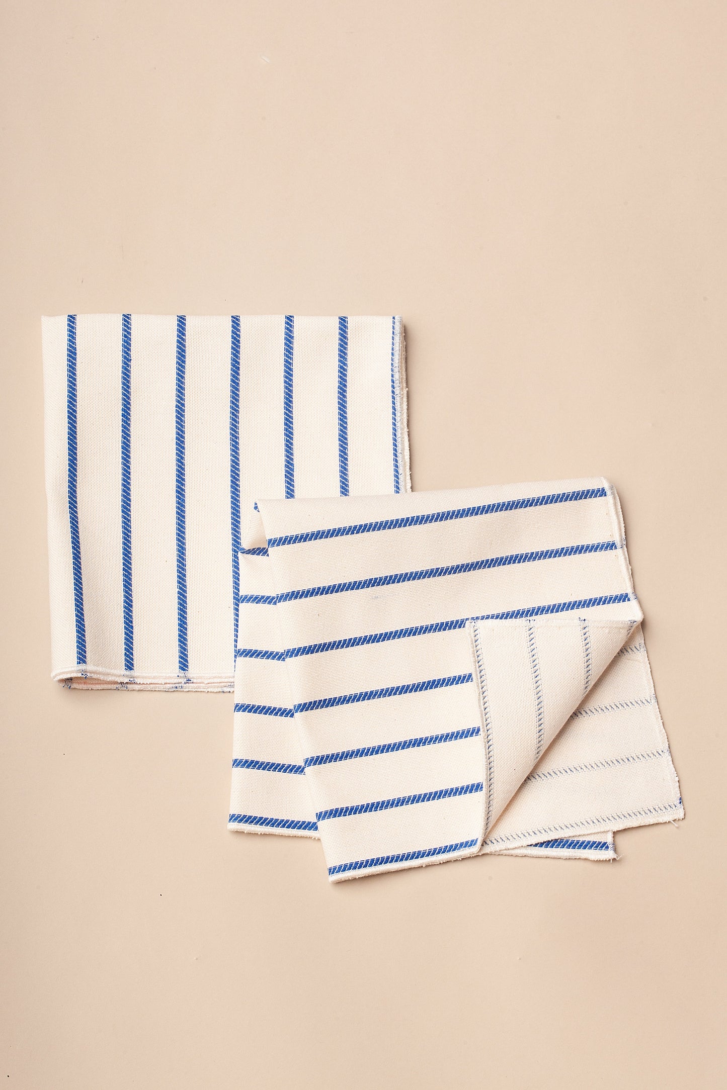 Servilletas de algodón blanco con rayas azules, estilo moderno y elegante, ideales para mesas contemporáneas.