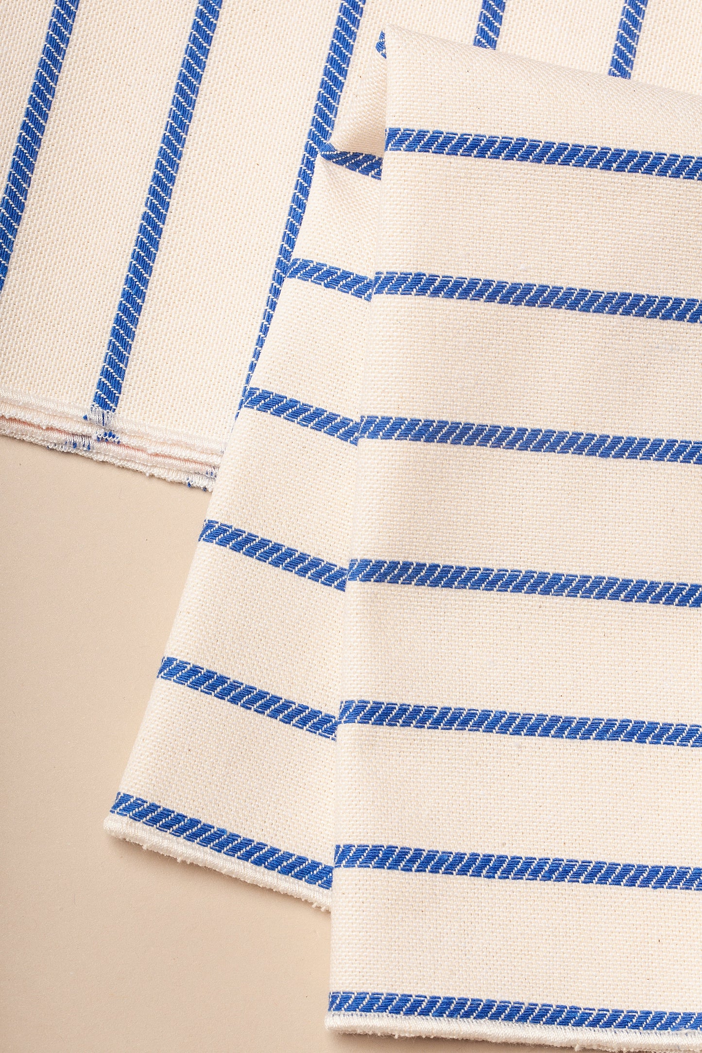 Tela de algodón beige con rayas azules, perfecta para decoración y manualidades.